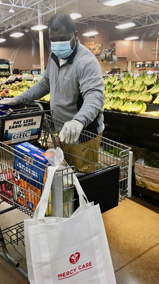 Charles Gardener, Adult Day Health coordinator, gloves-up and fills a cart of groceries on behalf of a client during senior shopping hours.