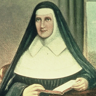 A woman dressed in a black and white nun’s habit sits indoors, holding an open book and looking slightly to the side. The background features a window and a curtain.