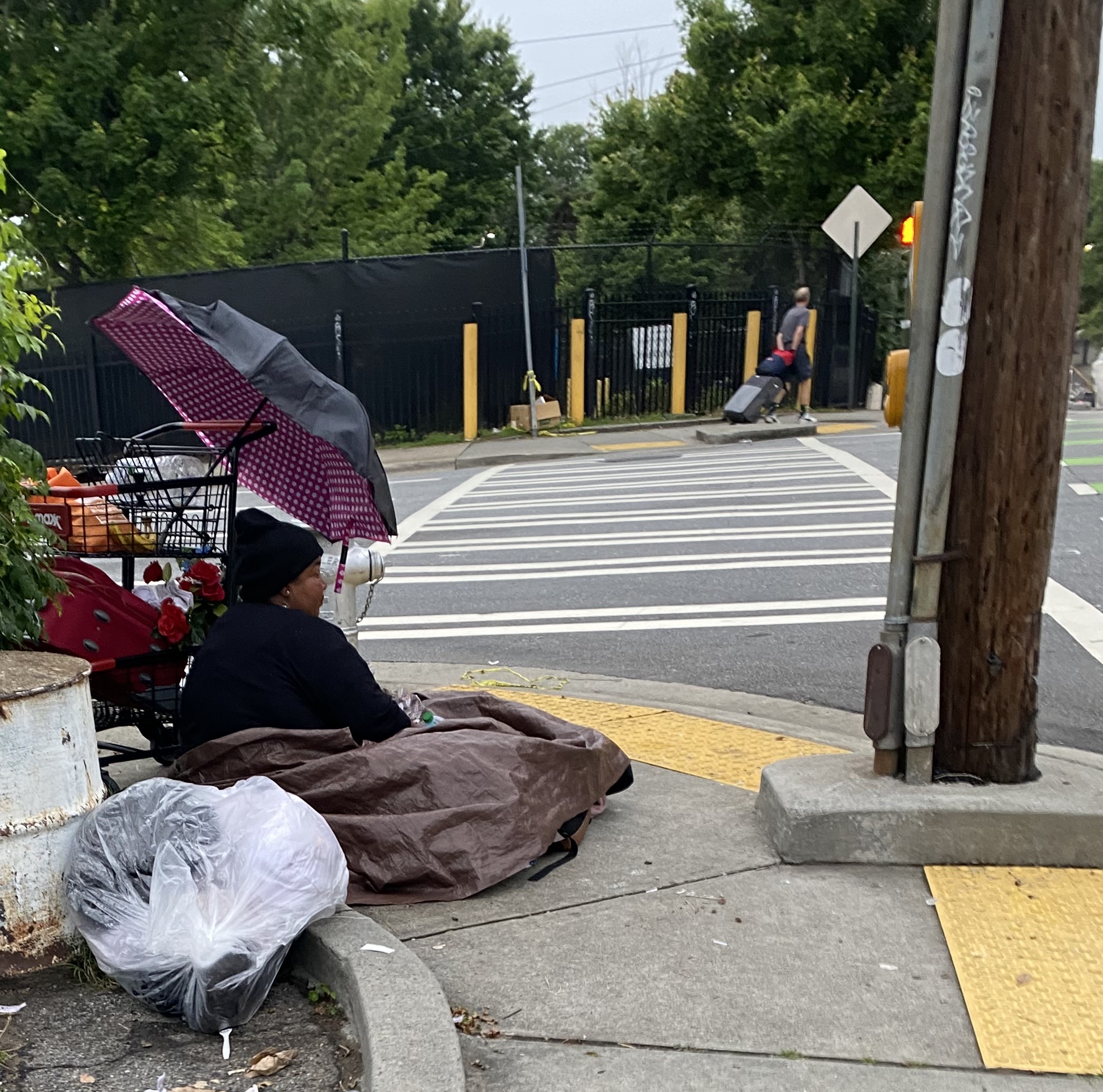 homeless woman sitting on street corner