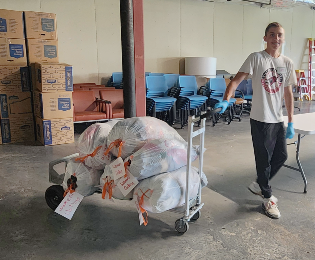 teen moving a cart of bags of donated womens' clothes